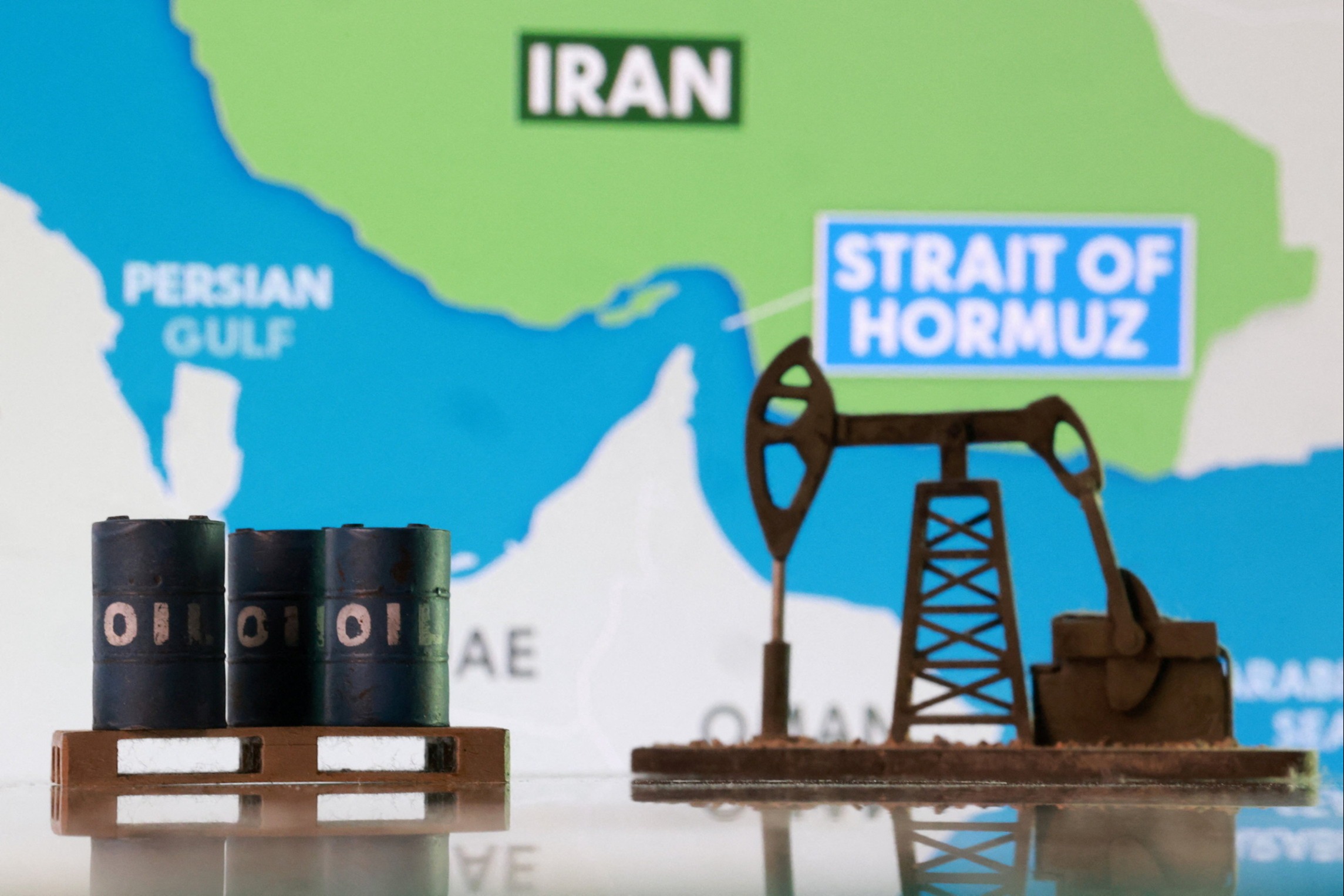 oil barrels, an oil pump jack and a map showing the Strait of Hormuz and Iran
