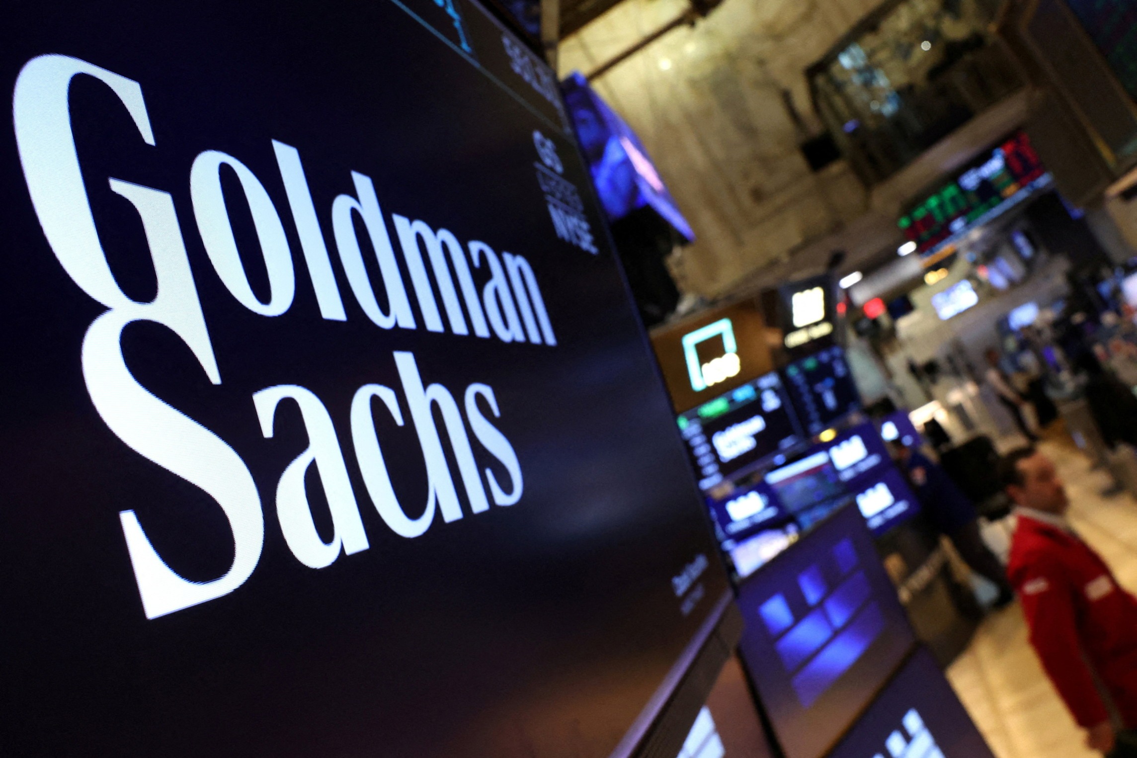 A screen displays the company logo for Goldman Sachs on the floor at the New York Stock Exchange
